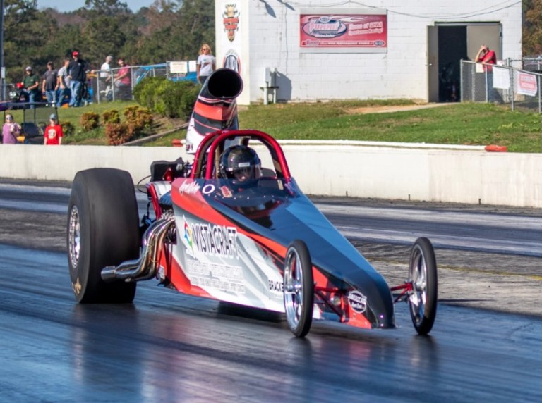 A vibrant wrapped dragster featuring bold graphics and branding for VistaCraft, showcased at a racing event.