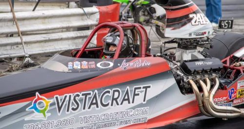 A vibrant wrapped dragster featuring bold graphics and branding for VistaCraft, showcased at a racing event.